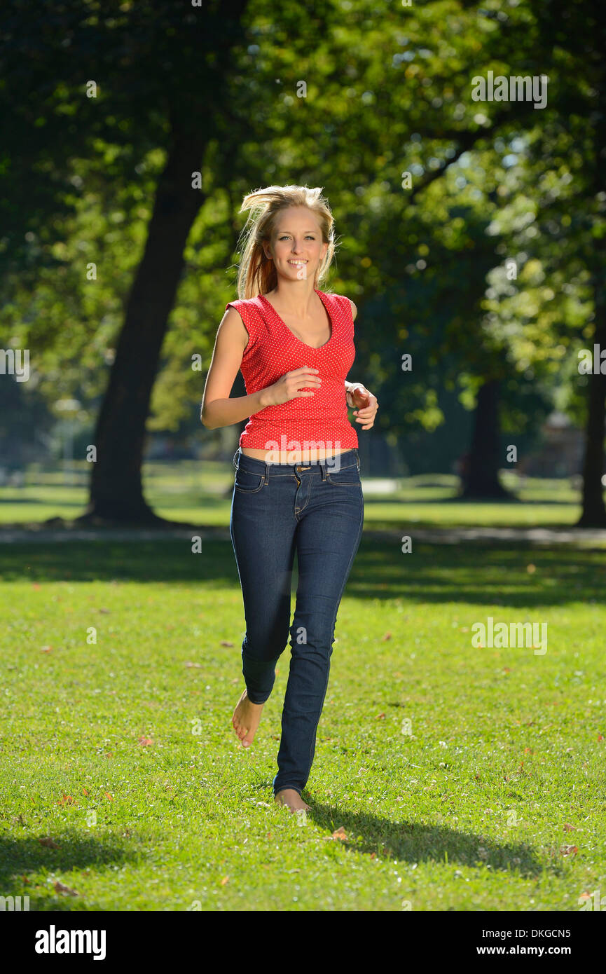 Junge, blonde Frau läuft in einem park Stockfoto