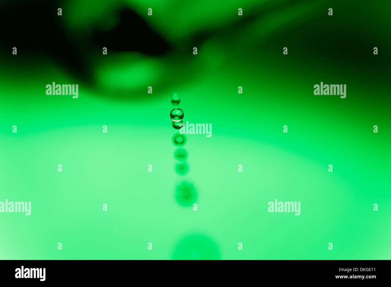 Wassertropfen tropft aus einem Wasserhahn, mit einem einzigen Tropfen im Fokus Stockfoto