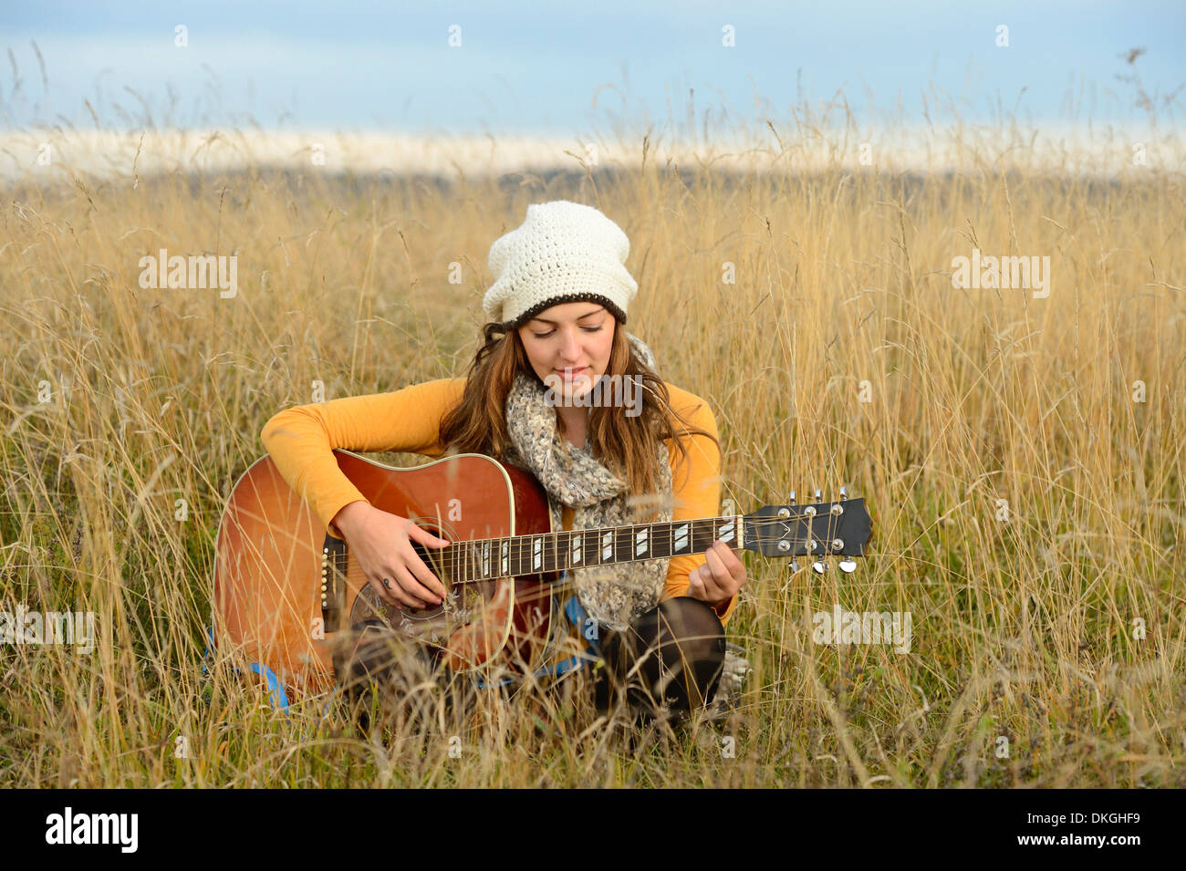 Junge Frau spielt Gitarre im Bereich Stockfoto