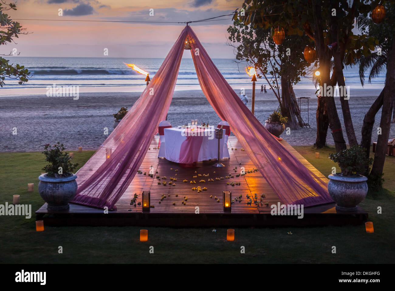 Romantischer Tisch zwei Pärchen Bali Strand Kerze Platten Essen Sonnenuntergang Asien rosa Vorhang Luxus Service Angebot touristischer Art hotel Stockfoto