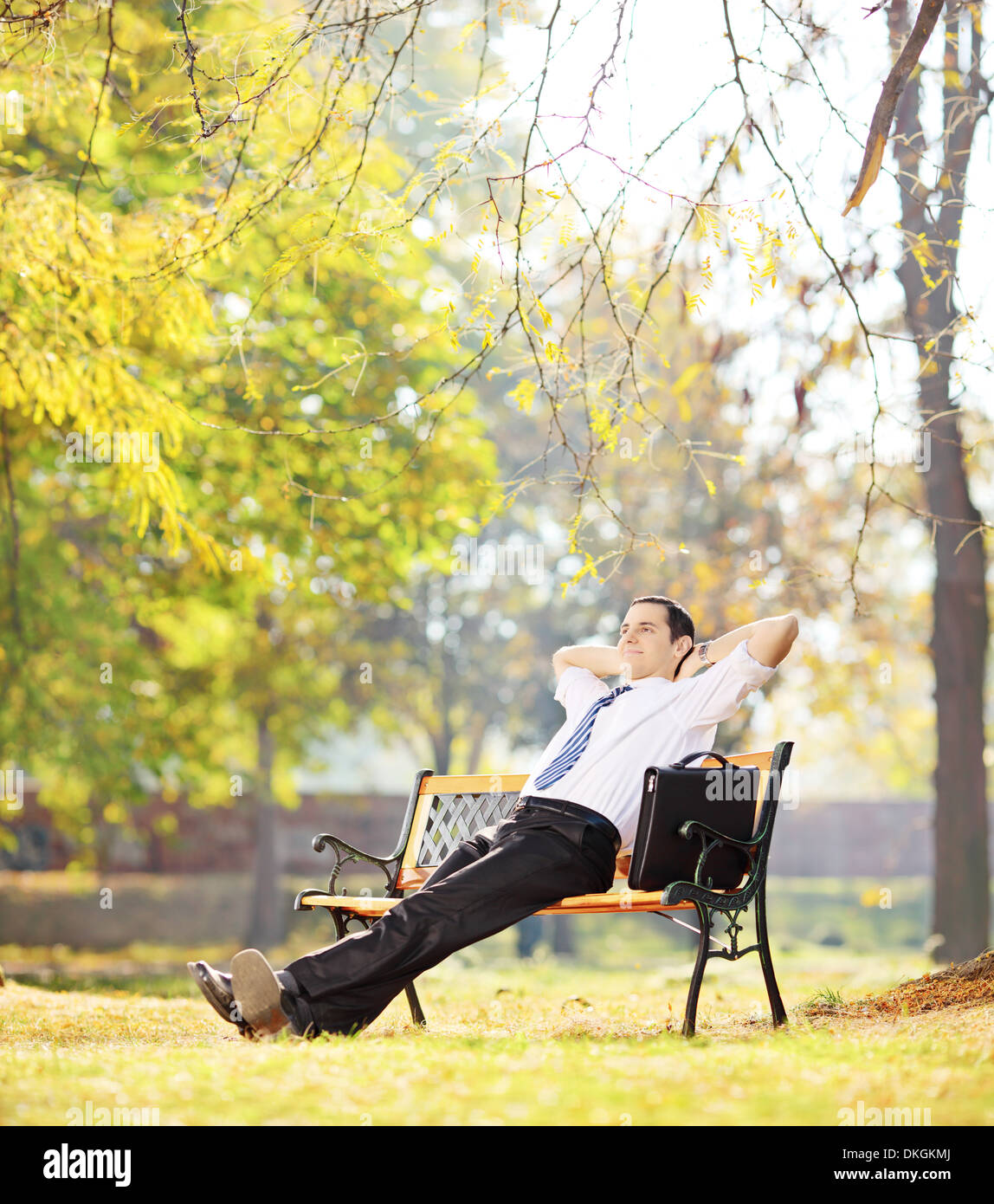 Junge Unternehmer sitzen auf einer Holzbank und entspannen in einem park Stockfoto