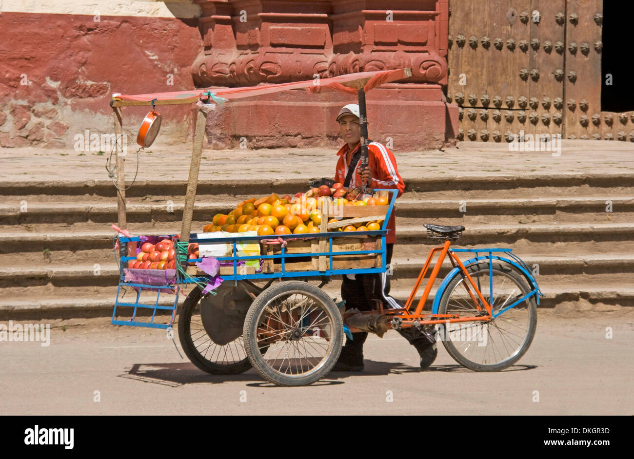 Junger Mann, Verkauf von Orangen aus Fahrrad Pedal Wagen auf der Straße vor der Kirche in Berg Dorf Huancavelica in Peru Stockfoto