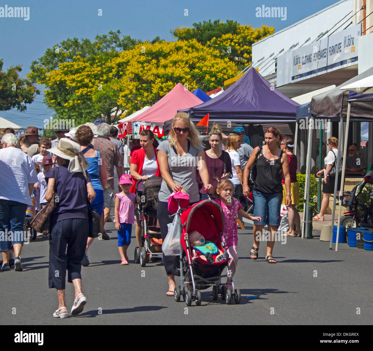 Menschen, darunter Frau mit Baby im Kinderwagen, Stände auf Straßenmarkt in Maryborough Queensland Australien durchsuchen Stockfoto