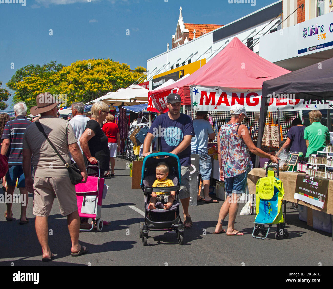 Menschen, einschließlich des Menschen mit Baby im Kinderwagen, Stände auf Straßenmarkt in Maryborough Queensland Australien durchsuchen Stockfoto