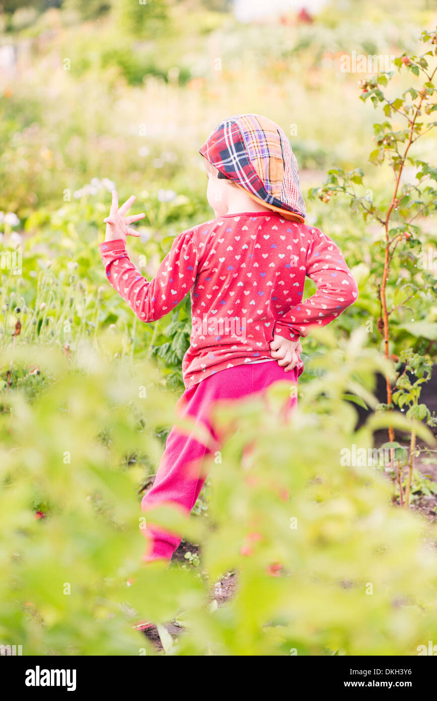 Rückansicht des jungen Kind stehend im Garten ihre Hand zu studieren Stockfoto
