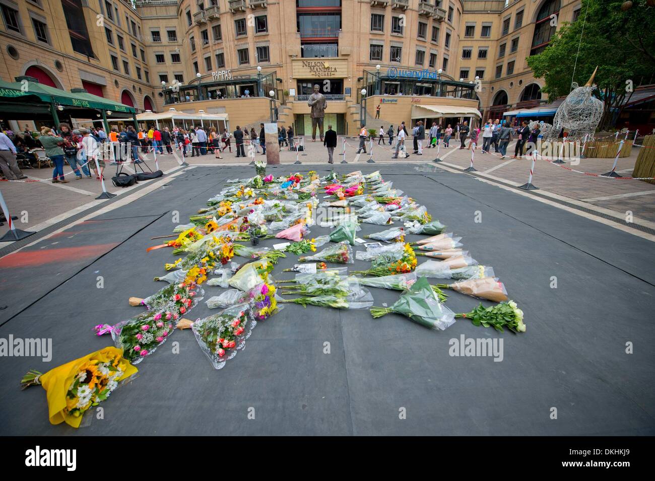 JOHANNESBURG, Südafrika: Menschen legen Blumen am Nelson Mandela Square, auf 6. Dezember 2013 in Houghton, Johannesburg, Südafrika. Trauernde haben seit den frühen Stunden des morgens ihre Aufwartung eingeholt. Der Vater der Nation, Nelson Mandela, Tata Madiba, ruhig am Abend des 5. Dezember 2013 in seinem Haus in Houghton mit Familie verstorben. (Foto von Gallo Images / Foto24 / Nicolene Olckers) Stockfoto