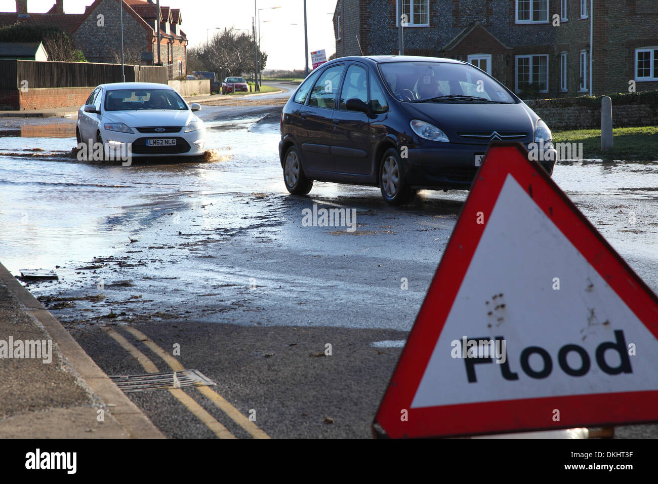 Starke Regenfälle und Stürme treffen Großbritannien, Autos werden hier gesehen, die durch Hochwasser fahren, vorbei an einem Hochwasserwarnschild. Stockfoto