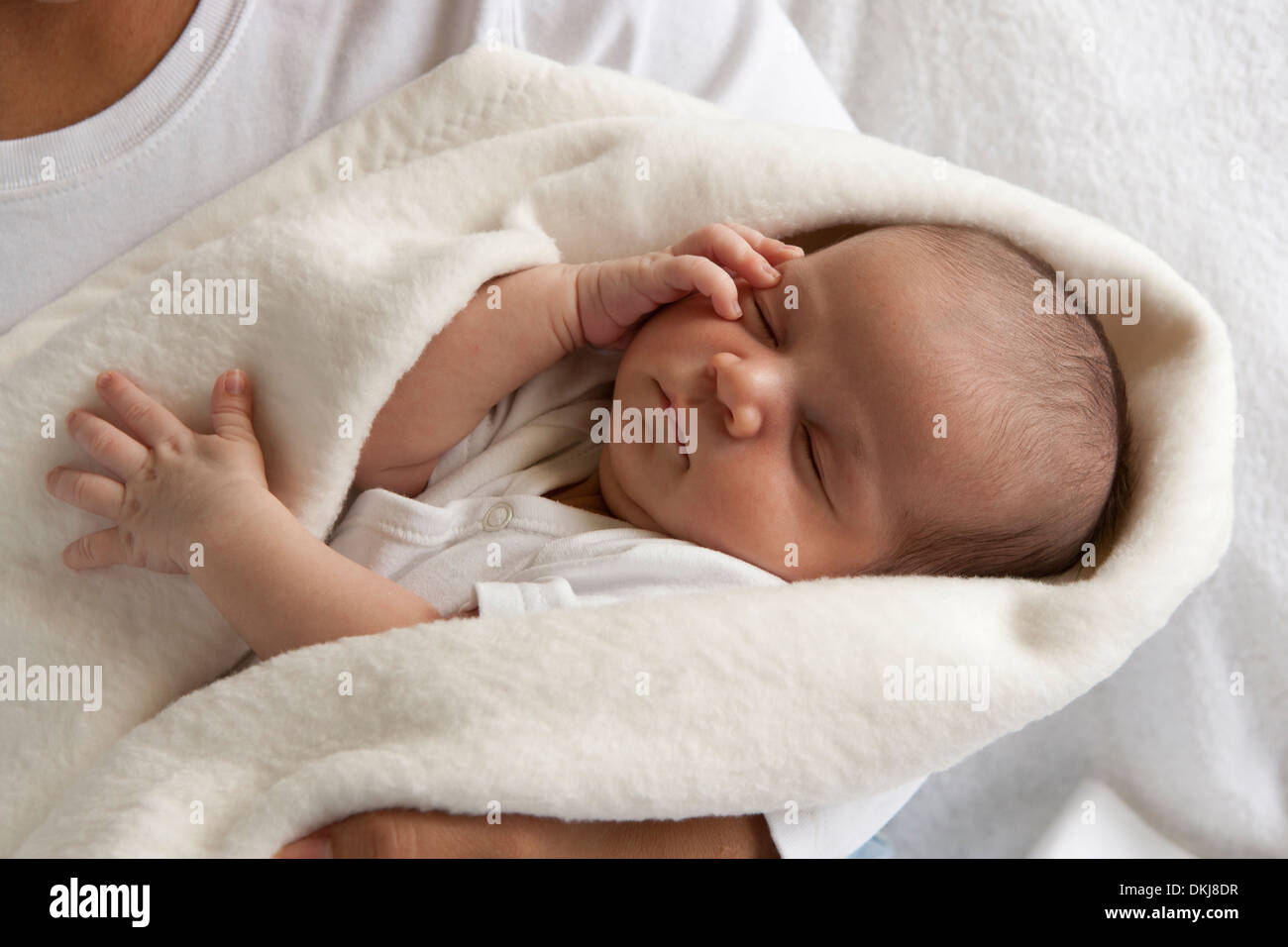 Neugeborenes Baby eingewickelt in ein Tuch über die Mütter Arme Stockfoto