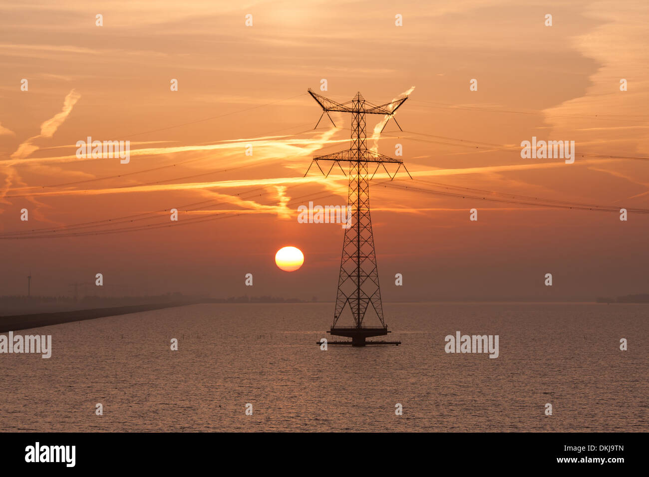 Sonnenaufgang über dem niederländischen Meer mit der Silhouette eines Strommastes Stockfoto