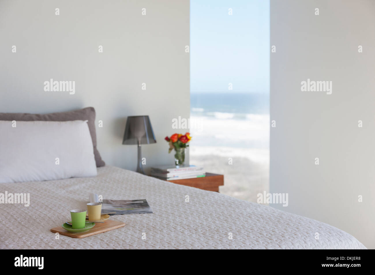 Tablett mit Espresso-Tassen auf Bett im Schlafzimmer mit Blick aufs Meer Stockfoto