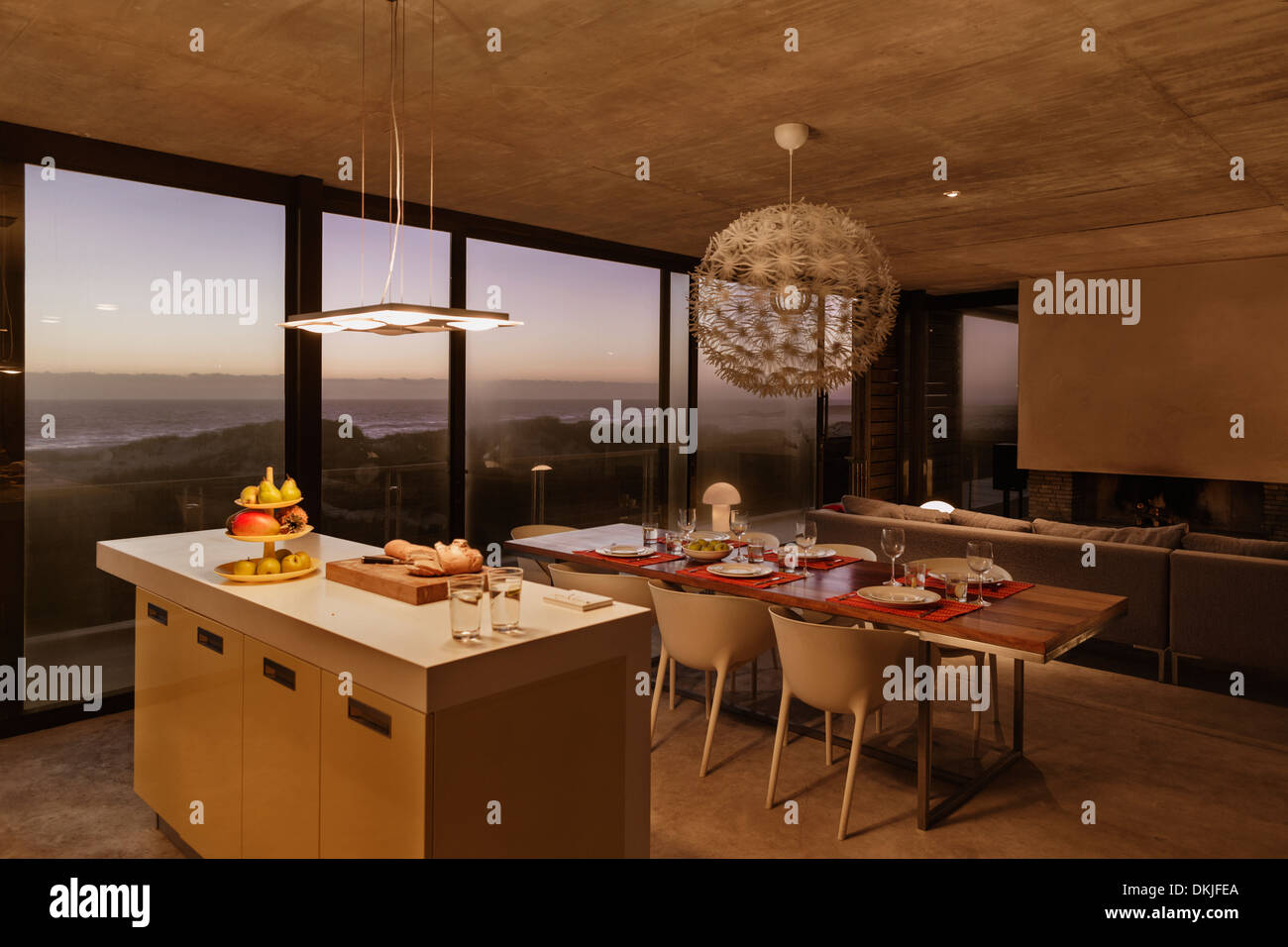 Frühstücks-Bar und Esstisch in modernen Küche mit Blick auf Meer in der Abenddämmerung Stockfoto
