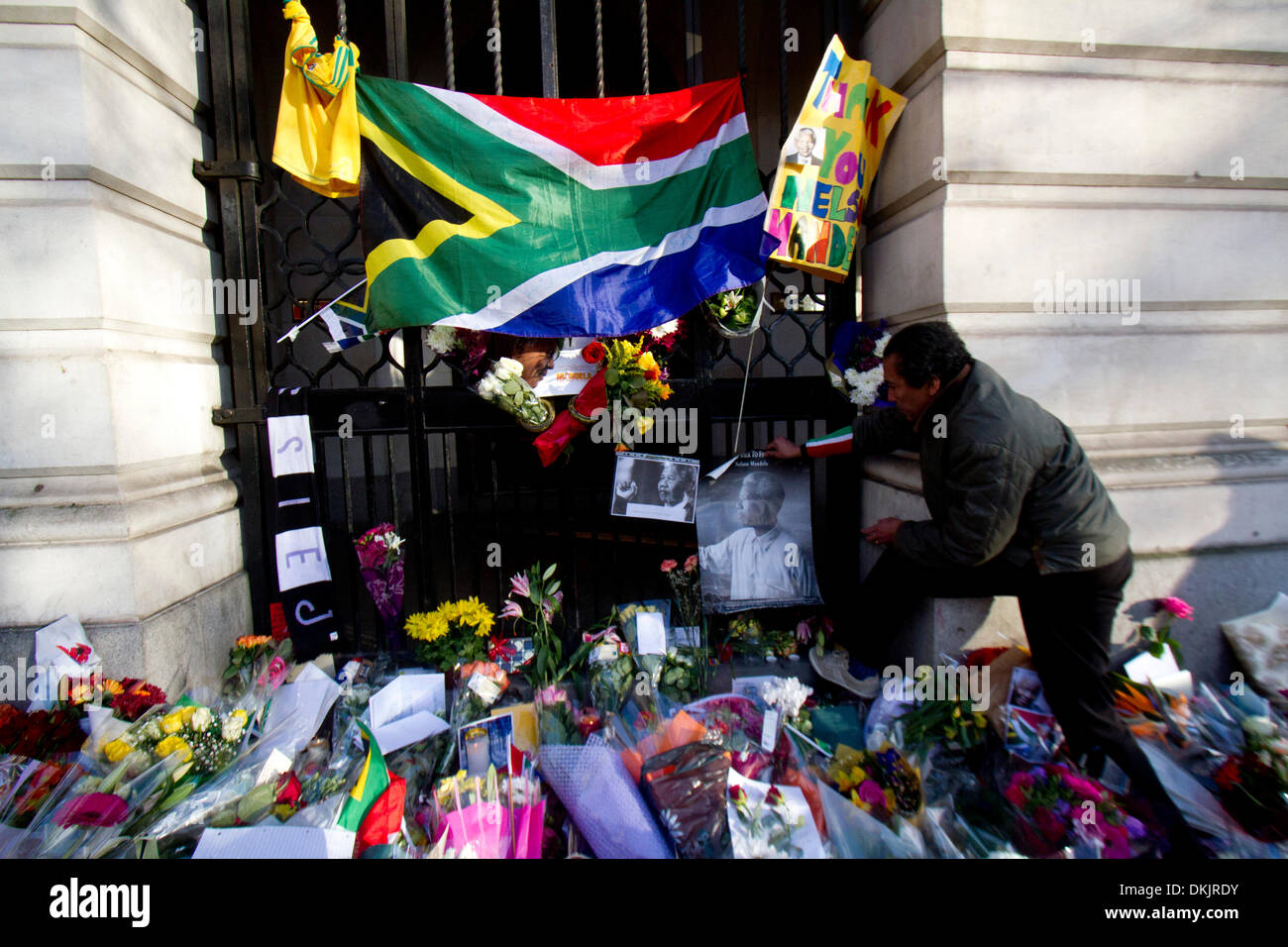 London UK. 6. Dezember 2013. Ein Mann legt ein Bild zum ehemaligen Südafrikas Präsident Nelson Mandela 1918-2013 starb gestern im Alter von 95 außerhalb der South Africa House in London. Nelson Mandela wurde zum ersten schwarzen Präsidenten, ins Gefängnis geworfen wurde, nachdem er gegen die Apartheid und eine rassisch geteilte Südafrika Credit warb: Amer Ghazzal/Alamy Live-Nachrichten Stockfoto