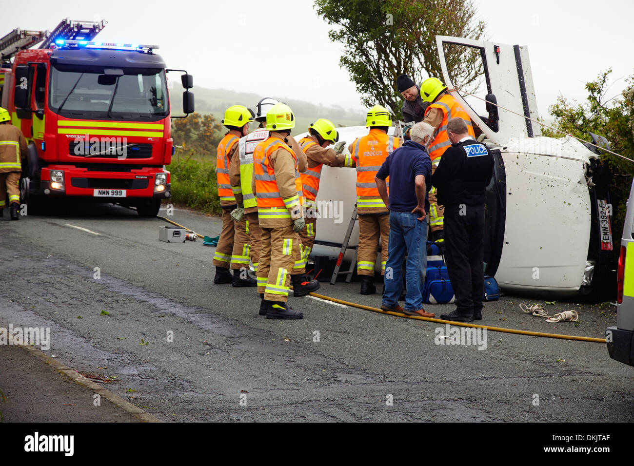 Treiber gerettet werden durch Feuerwehrleute nach Van auf der Küstenstraße in der Nähe von Peel, Insel Man umgeworfen Stockfoto