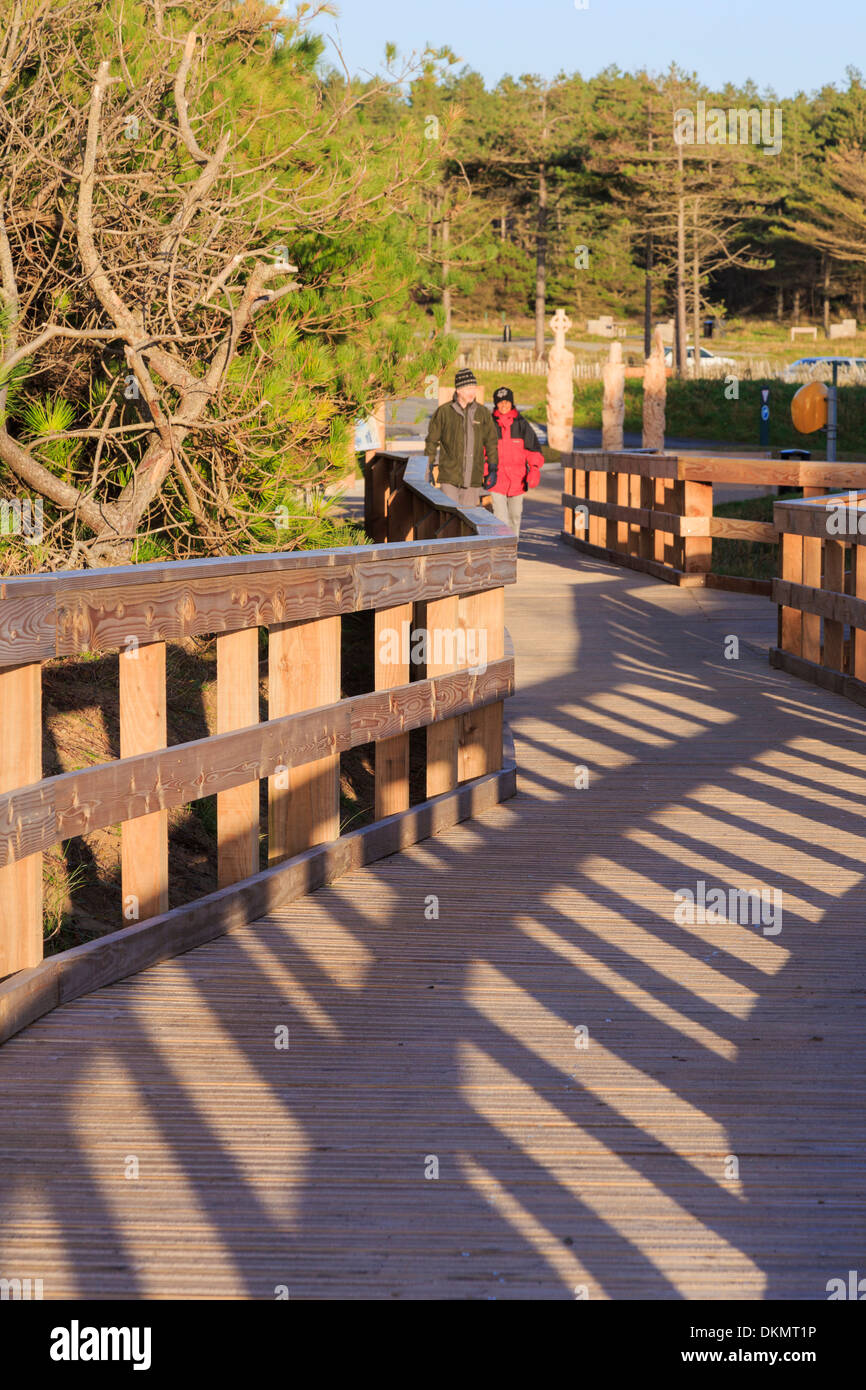 Menschen zu Fuß auf der neuen Promenade führt vom Strand zum Parkplatz in Newborough Wald, Isle of Anglesey, North Wales, UK, Großbritannien Stockfoto