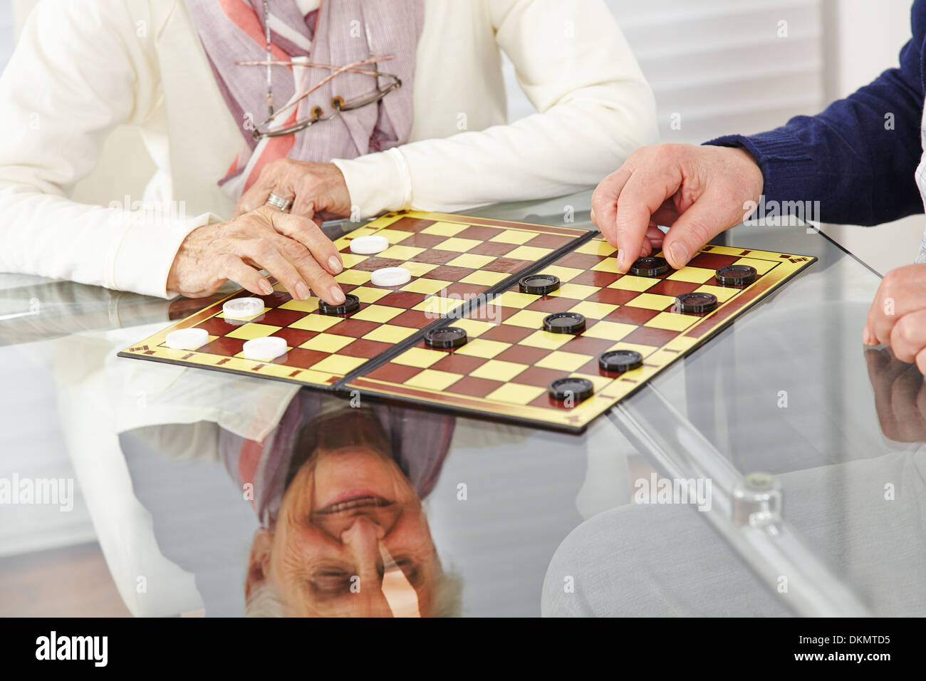 Glücklich Senioren Paar spielen Dame zu Hause Stockfoto