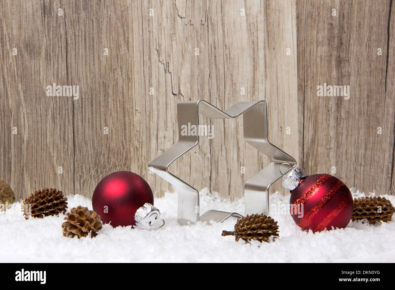 Weihnachts-Dekoration mit hölzernen Hintergrund, Schnee, Weihnachtskugeln rot, Weihnachtsstern und Tannenzapfen Stockfoto