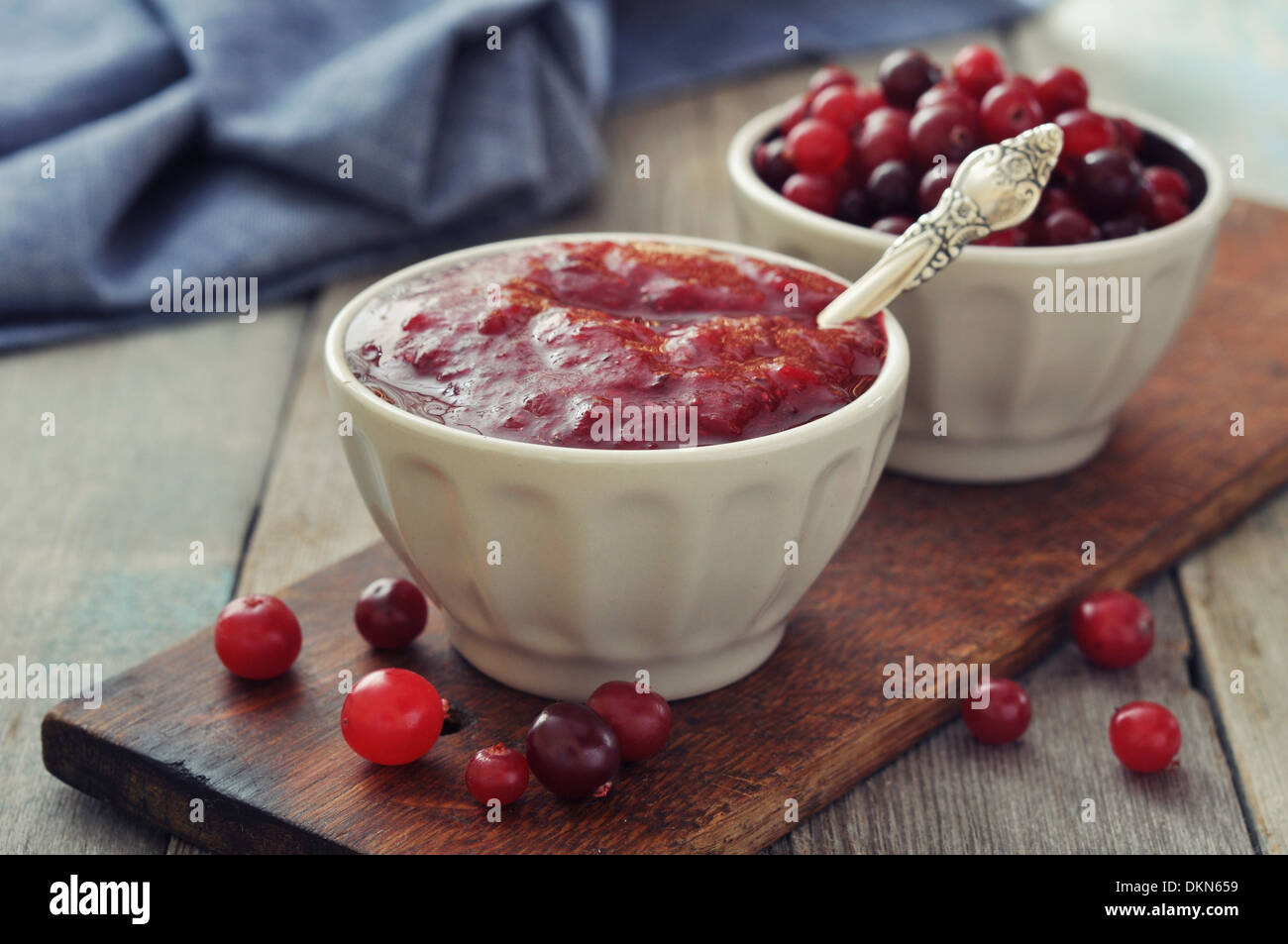 Cranberry-Sauce in Keramikschale mit frischen Beeren auf hölzernen Hintergrund Stockfoto