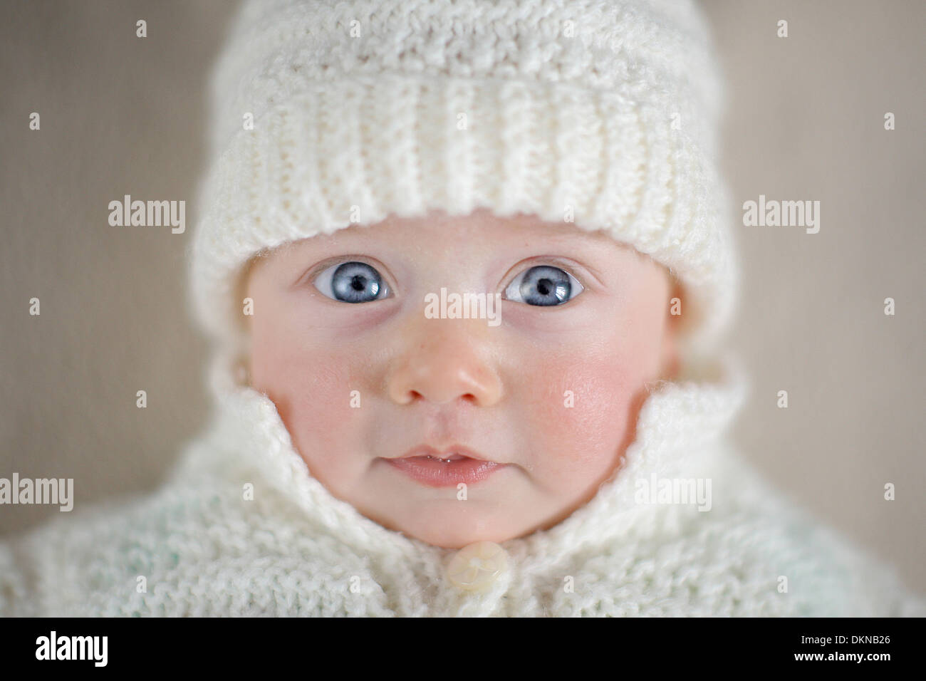 Baby mit blauen Augen in weißen Wintermütze Stockfoto
