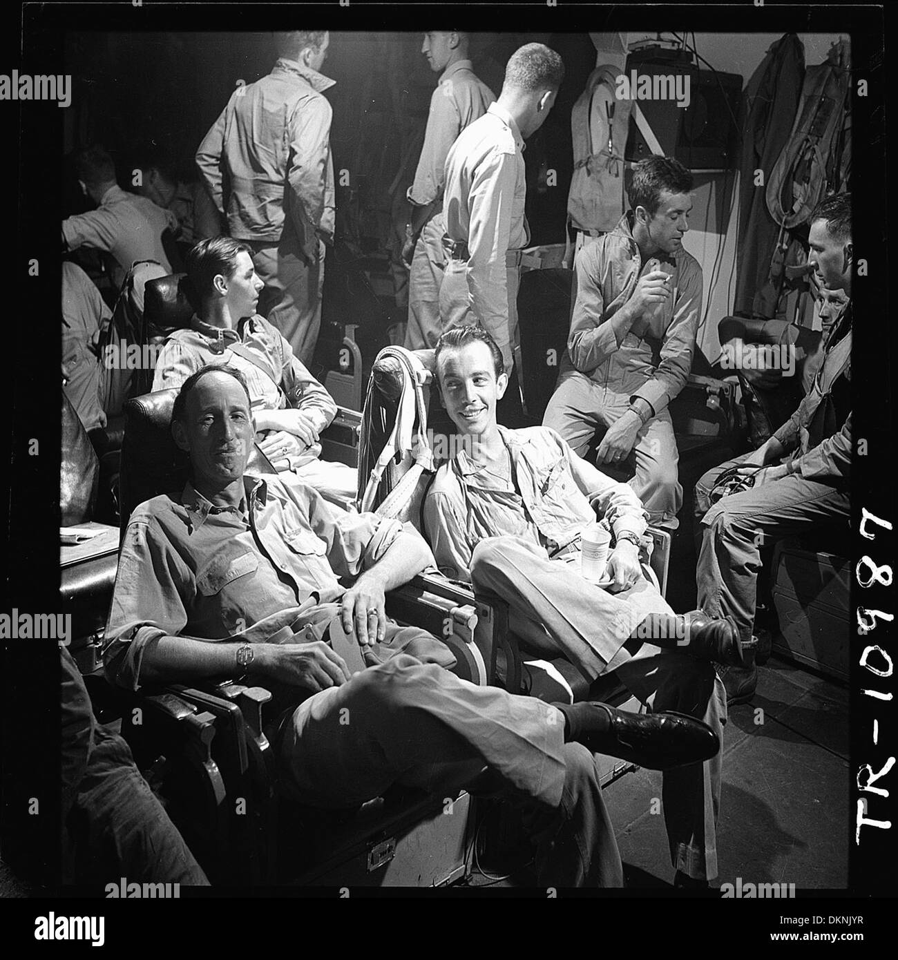 Dieses Bild zeigt Captain Stuart H. Ingersoll, Kommandant eines Flugzeugträgers der US Navy, lächelt entspannt, während er den Berichten der Piloten lauscht. Ingersoll' Führung spiegelt das ruhige Verhalten wider, das von Militärkommandeuren bei Stressoperationen erwartet wird. Stockfoto