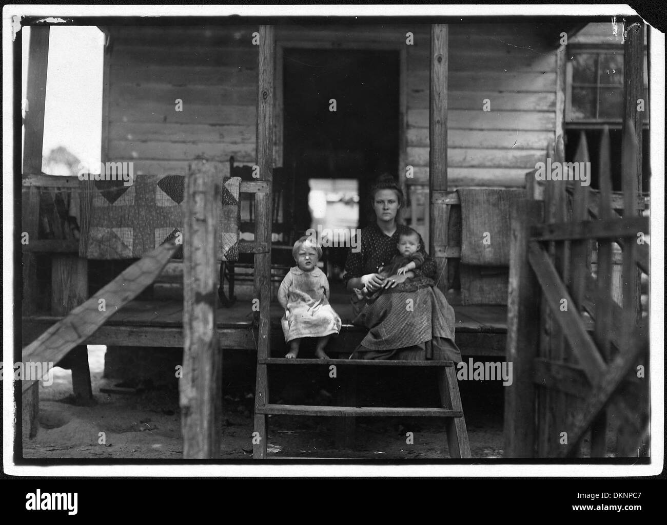 Dieses Foto zeigt Mrs. L. Bosher, der in einem baufälligen Baumwollmühlendorf lebt. Ihr Mann arbeitet seit vielen Jahren als Mühlenarbeiter und spiegelt die Schwierigkeiten wider, denen Familien in Industriemühlenstädten gegenüberstehen. Stockfoto