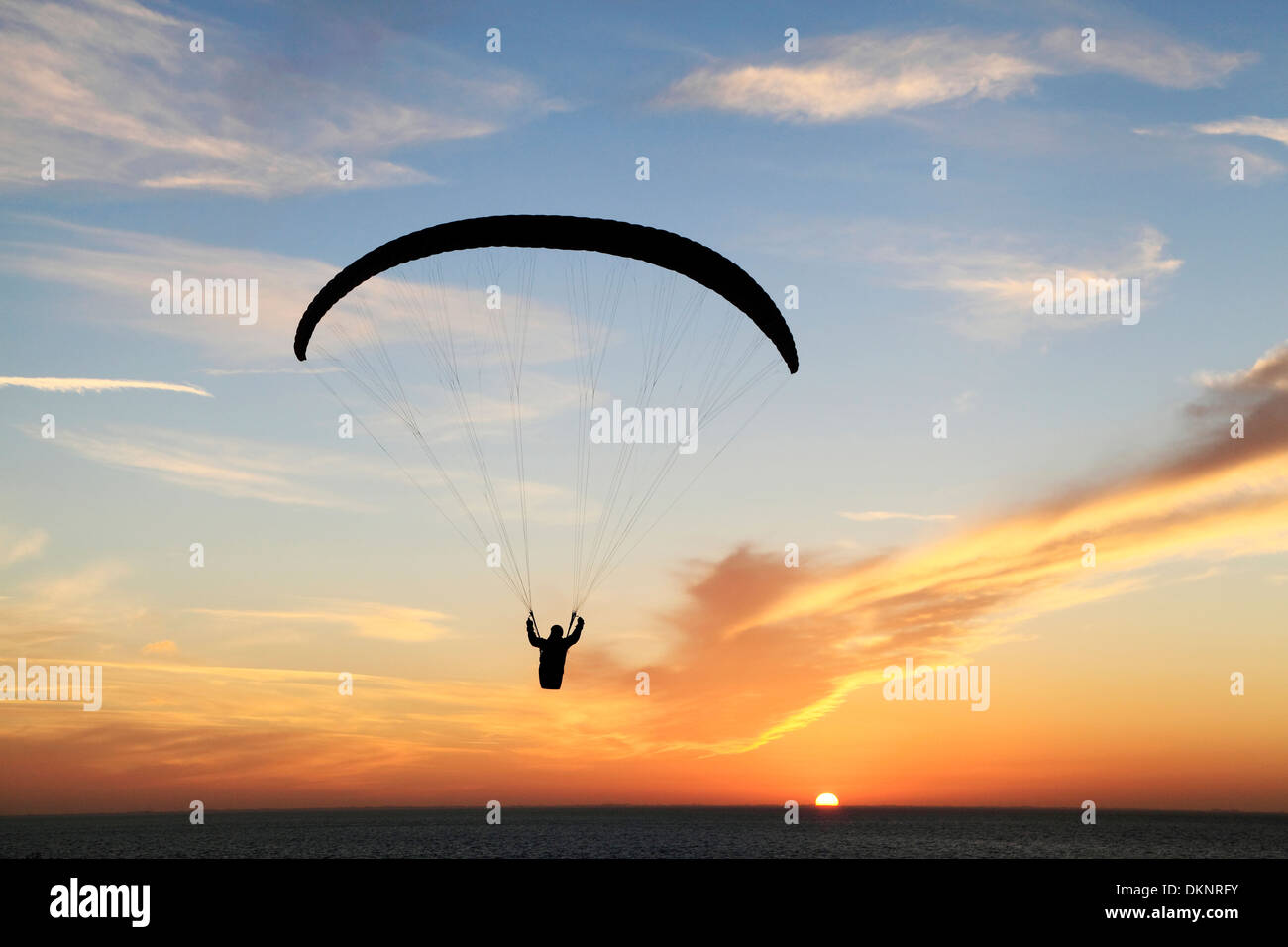 Hängegleiter bei Sonnenuntergang, Sonne Segelflugzeuge Mann Drachenfliegen Fallschirm Silhouette Silhouetten Einstellung Hunstanton Norfolk England UK Stockfoto