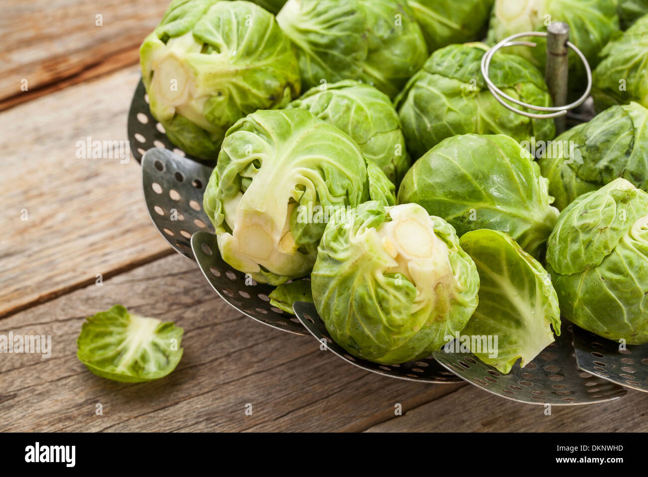 Rosenkohl in einem Metall Dämpfeinsatz auf Holztisch Stockfoto