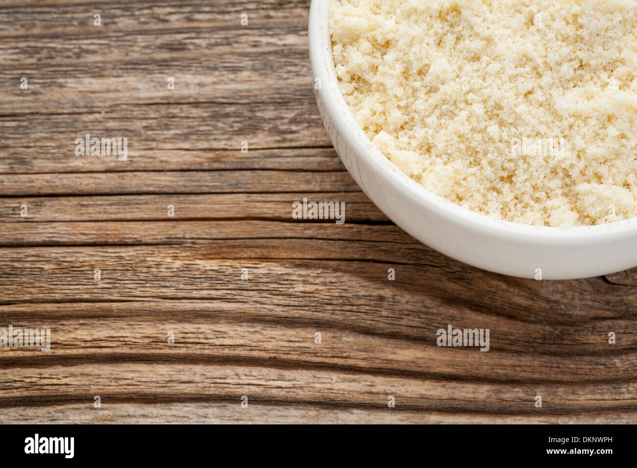 Mandel Mehl hoher Proteingehalt, wenig Kohlenhydrate, wenig Zucker und Gluten-frei - eine Keramikschale auf gemasertem Holz Hintergrund Stockfoto