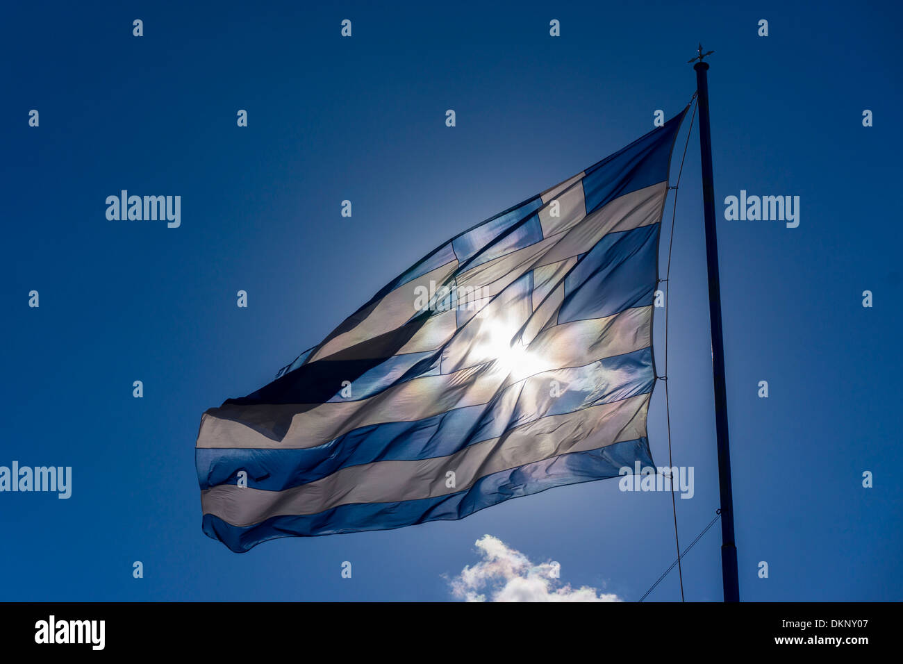 Große griechische Fahne flattert gegen Sonne gegen die Sonne, blauer Himmel mit weißen Wolken Stockfoto