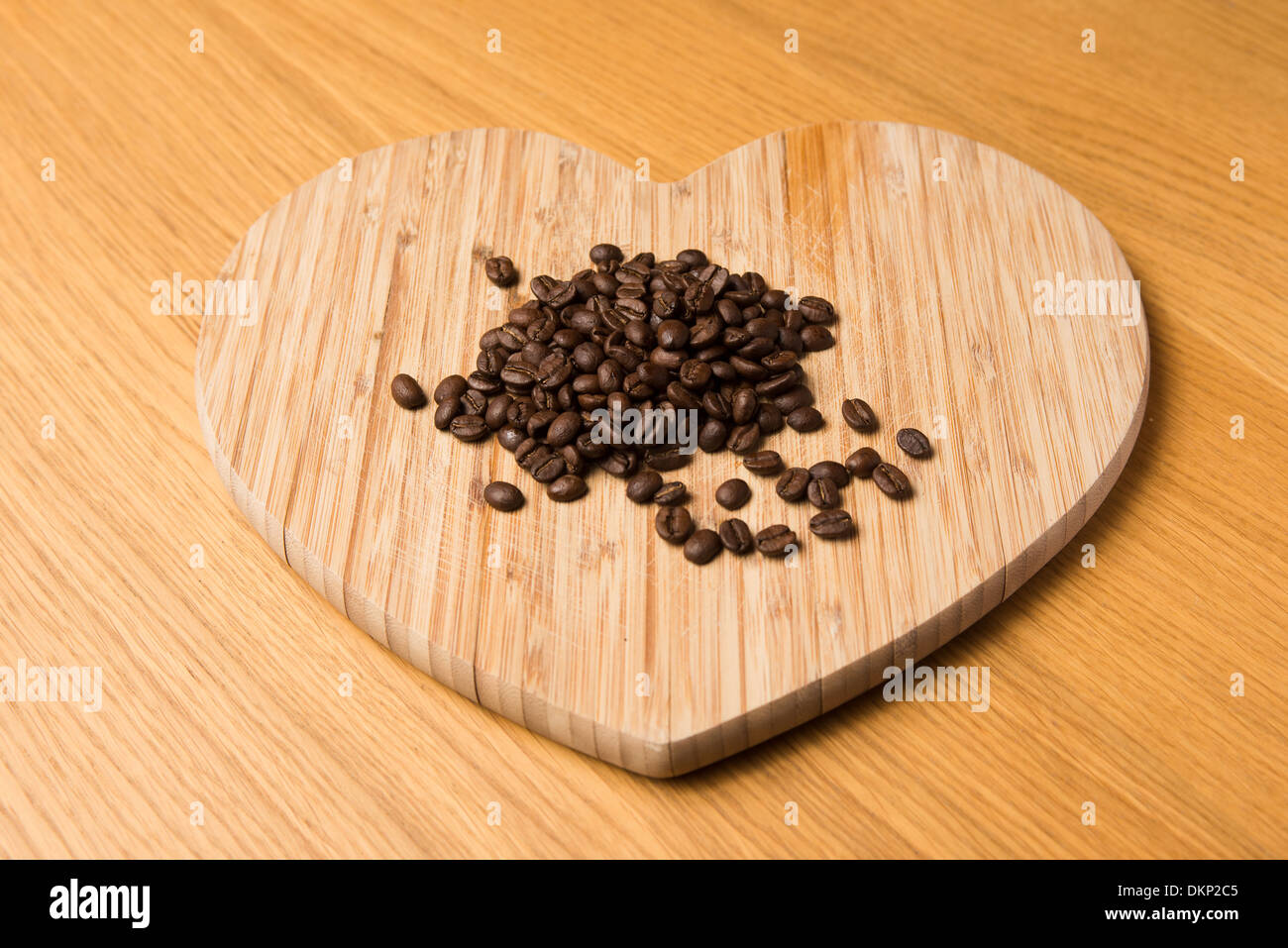 Braun geröstete Kaffeebohnen auf einer hölzernen herzförmigen Schneidebrett Stockfoto