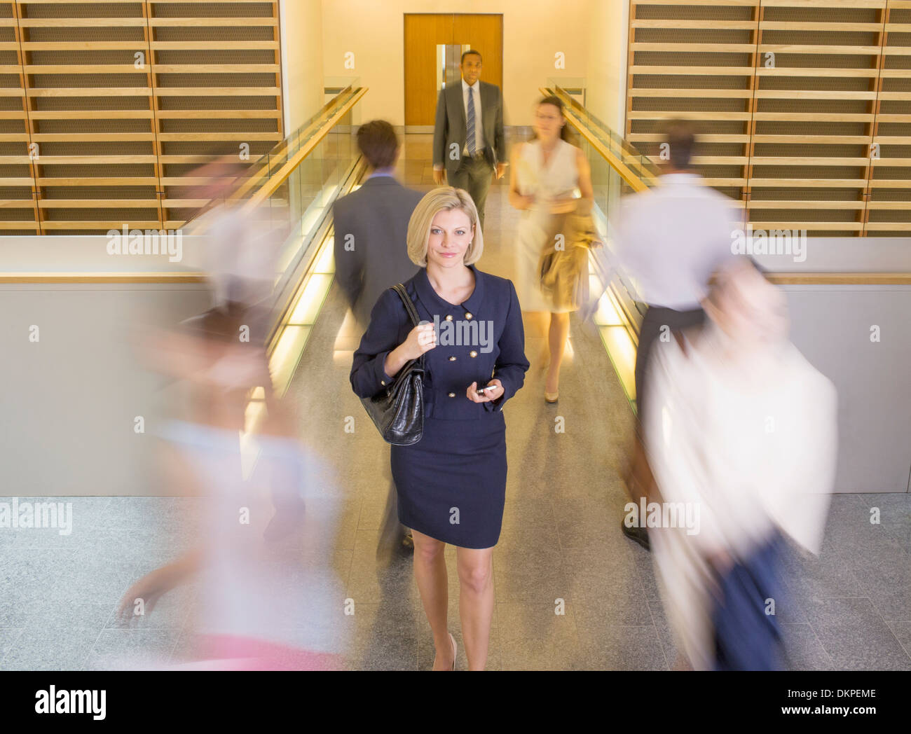 Geschäftsfrau, die zu Fuß in geschäftiges Büro Korridor Stockfoto