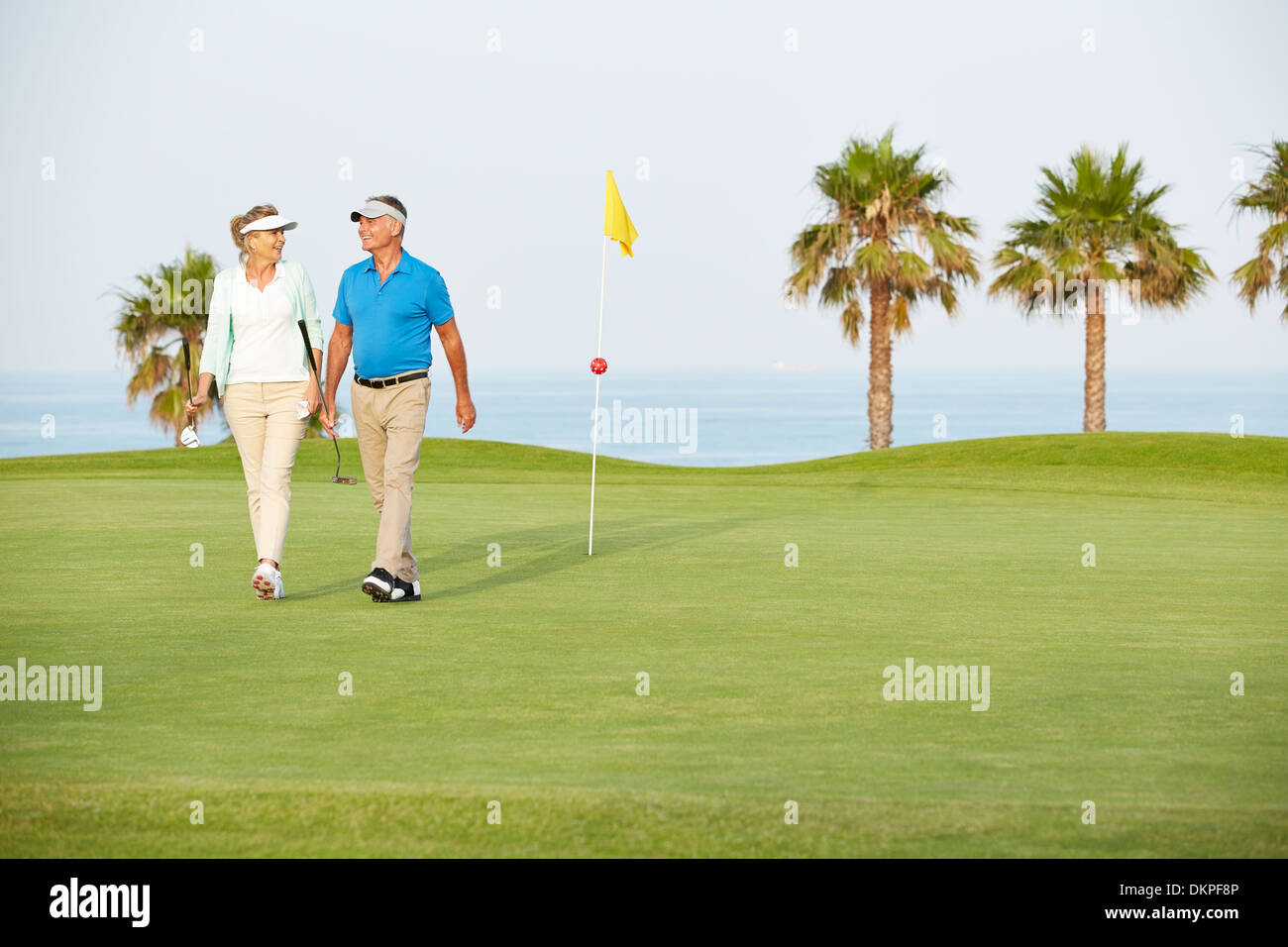Älteres Paar zu Fuß am Golfplatz Stockfoto