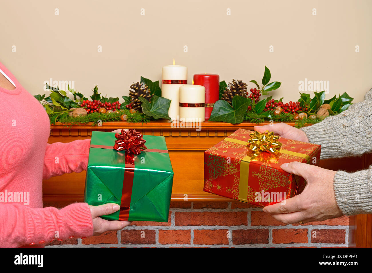 Ein paar zu Hause den Austausch von Weihnachtsgeschenke mit einem verzierten Kaminsims im Hintergrund. Stockfoto