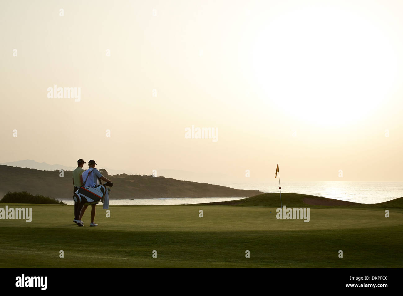Männer am Golfplatz bei Sonnenuntergang Stockfoto