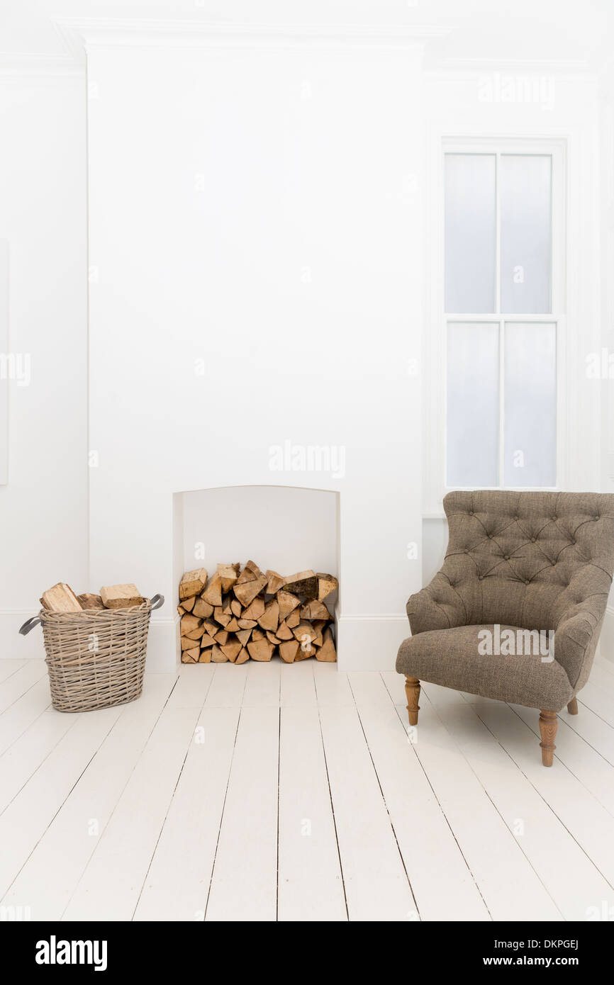 Brennholz und Sessel im Wohnzimmer Stockfoto