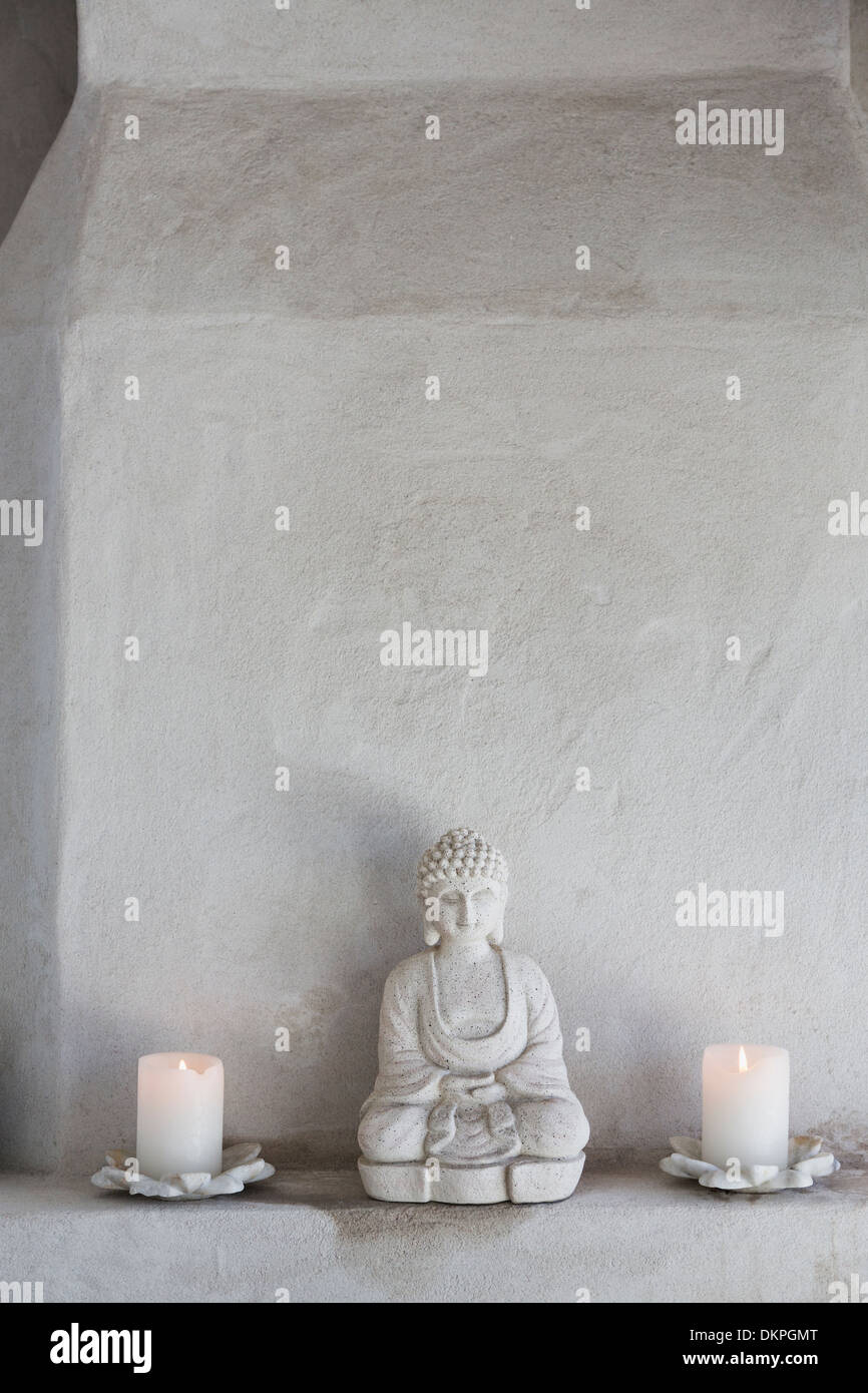 Buddha Figur und Kerzen auf Sims Stockfoto