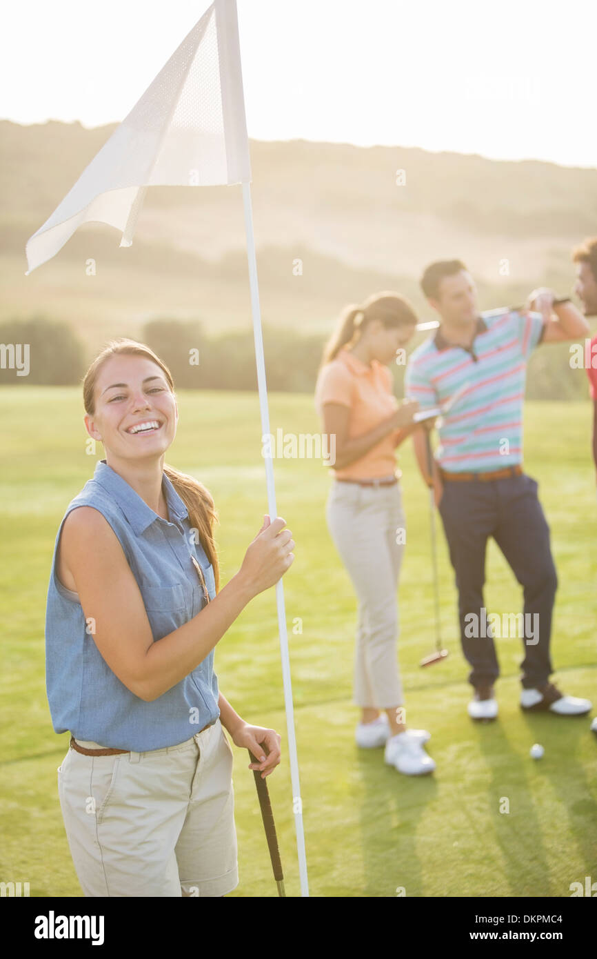 Lächelnde Frau hält Golf Fahne Stockfoto
