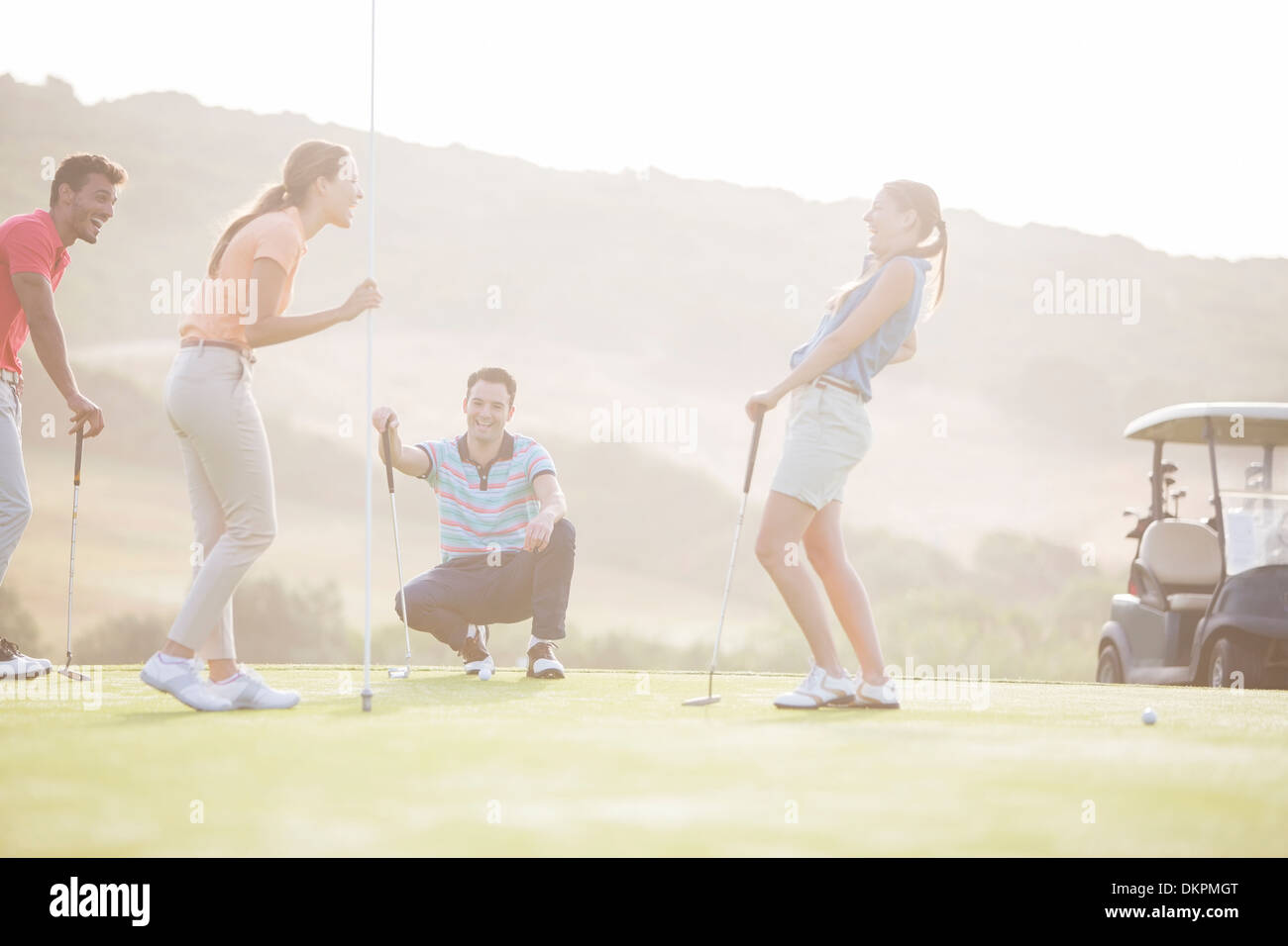 Freunde lachen in der Nähe von Loch am Golfplatz Stockfoto