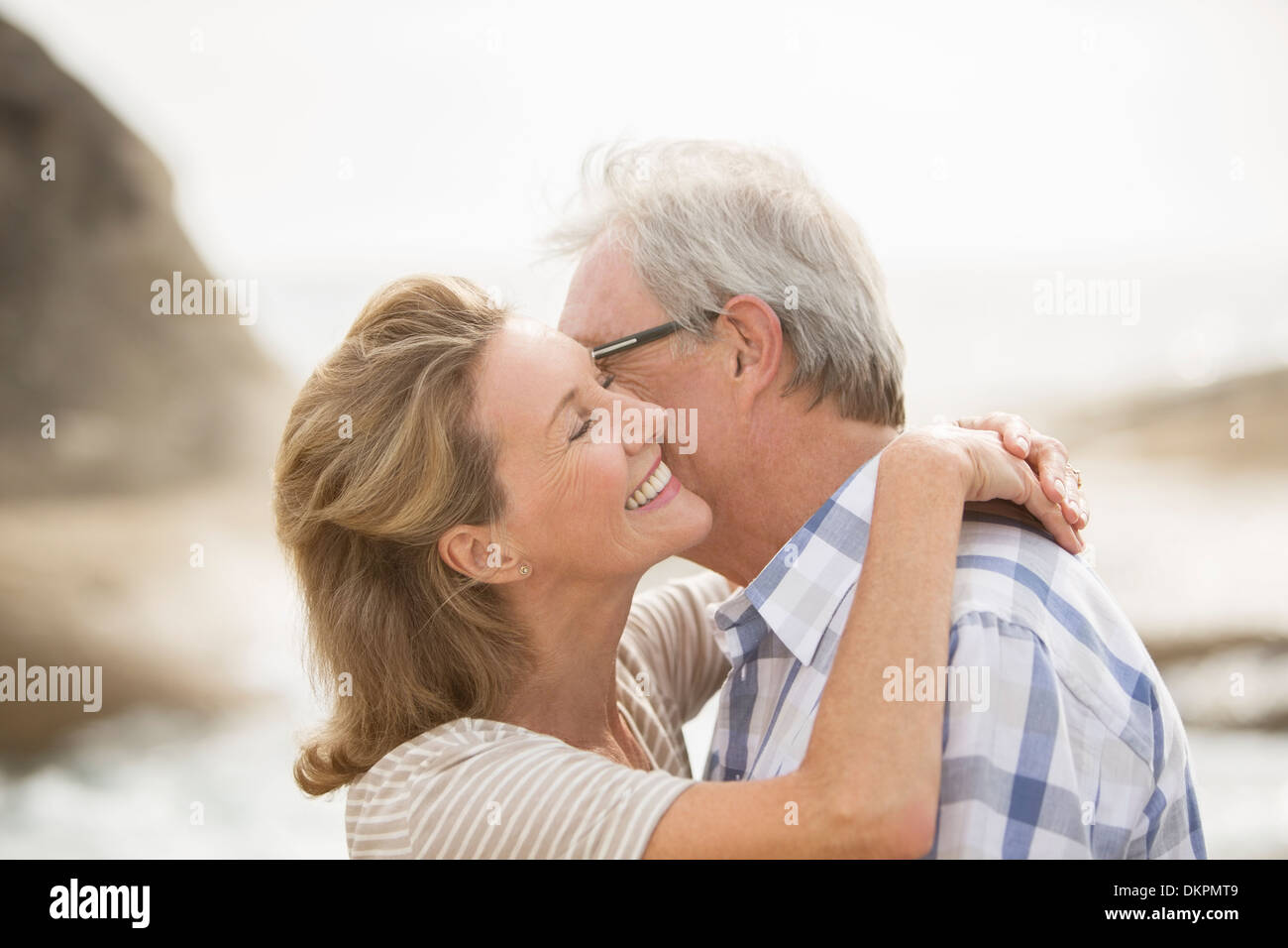 Älteres Paar küssen am Strand Stockfoto