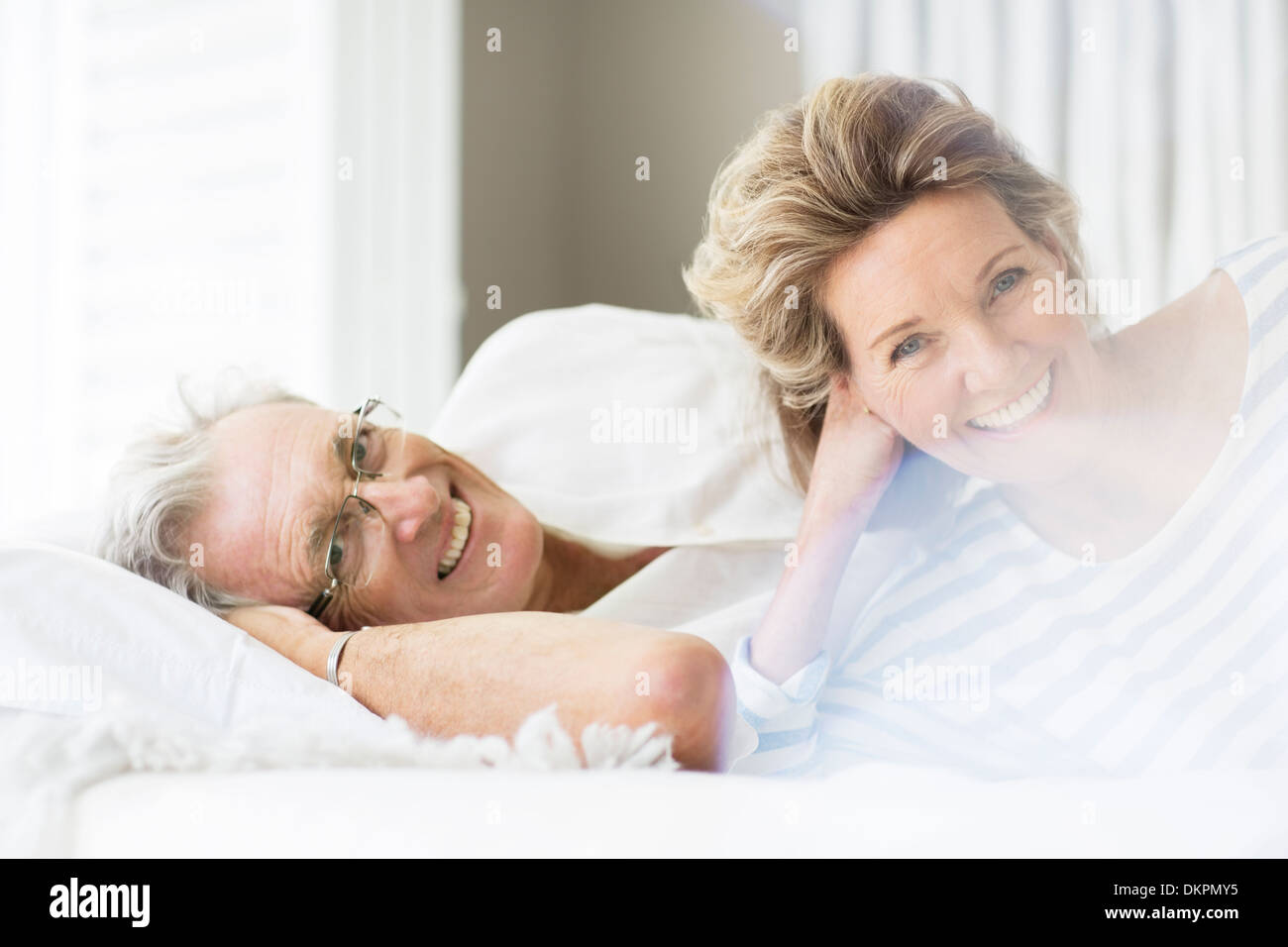 Älteres Ehepaar lächelnd auf Bett Stockfoto