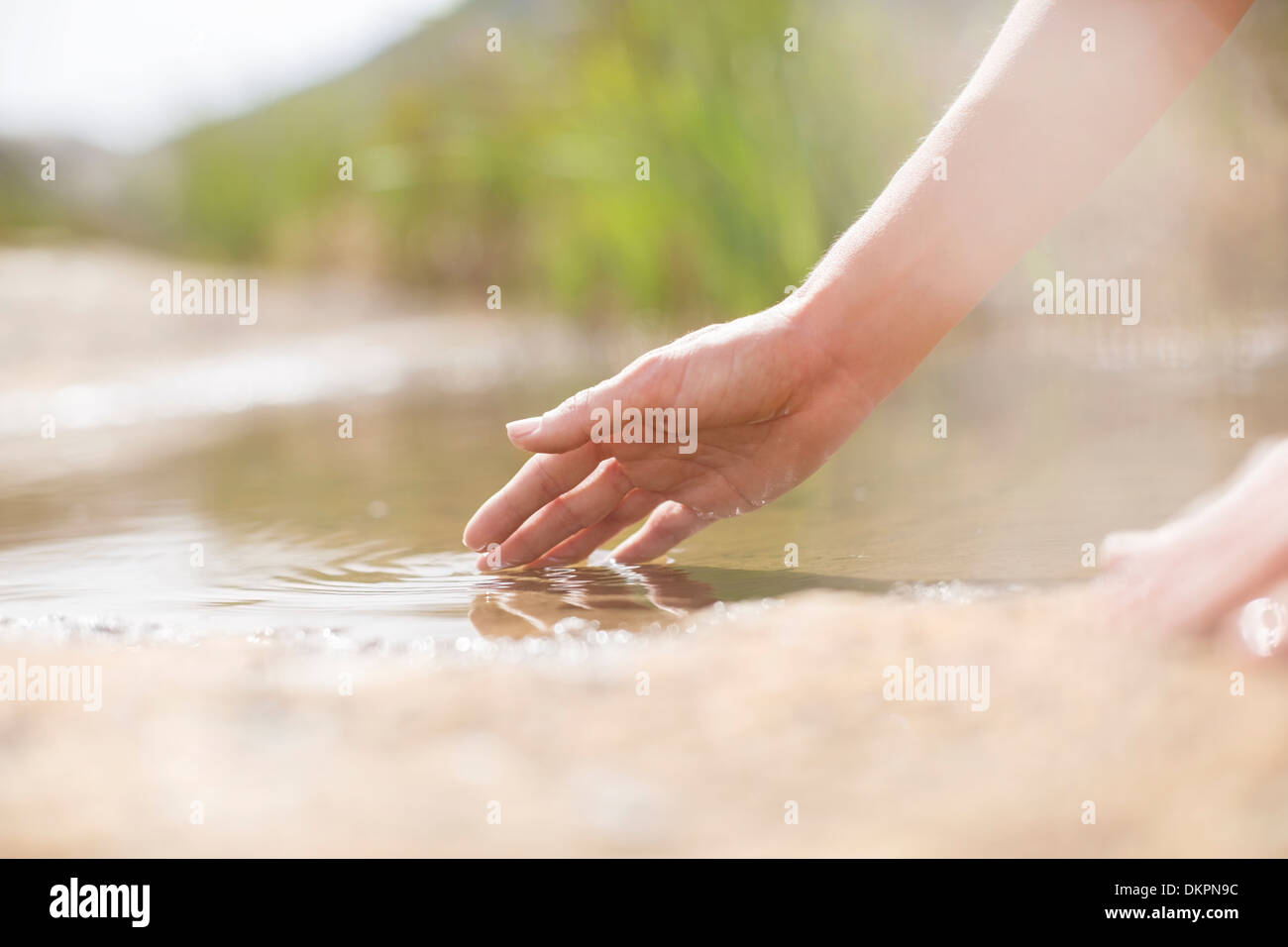 Frau Finger in ländlichen Teich eintauchen Stockfoto
