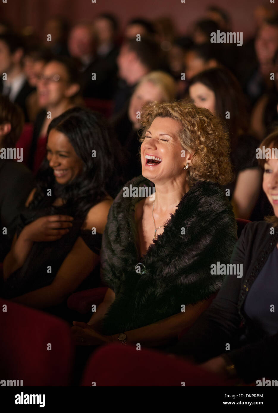 Im Theater-Publikum begeistert lachende Frau Stockfoto