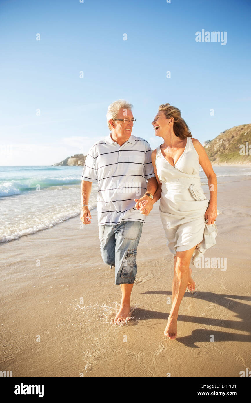 Älteres Paar in Brandung am Strand zu Fuß Stockfoto