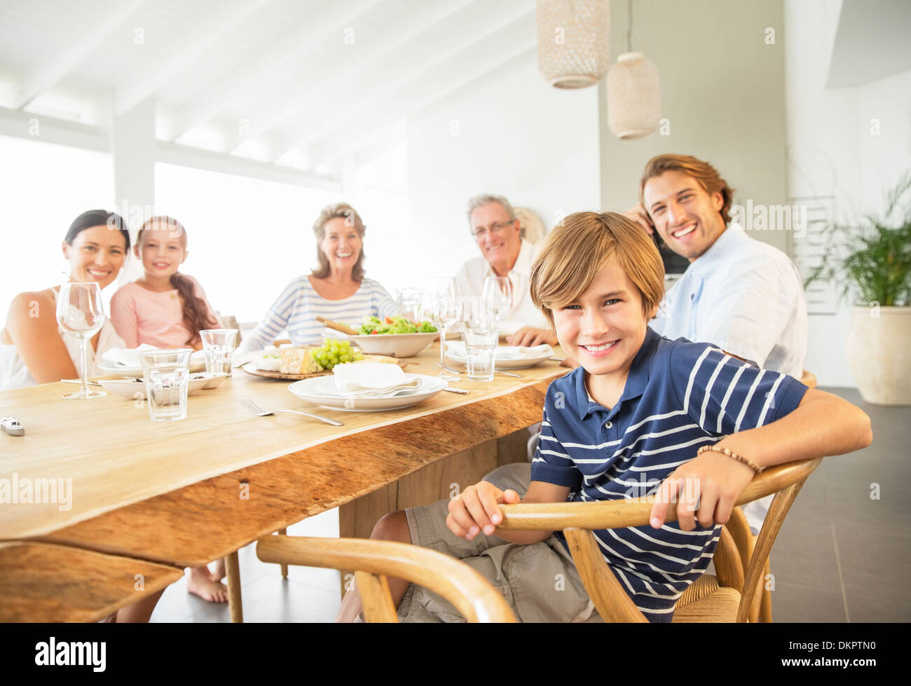 Familie zusammen am Tisch lächelnd Stockfoto