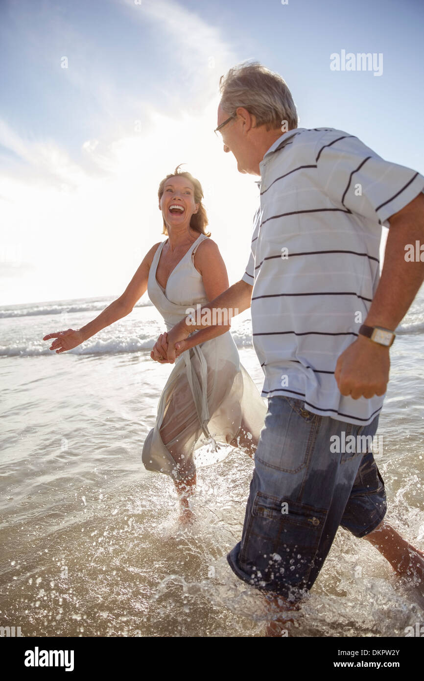 Älteres Ehepaar spielen in Wellen am Strand Stockfoto