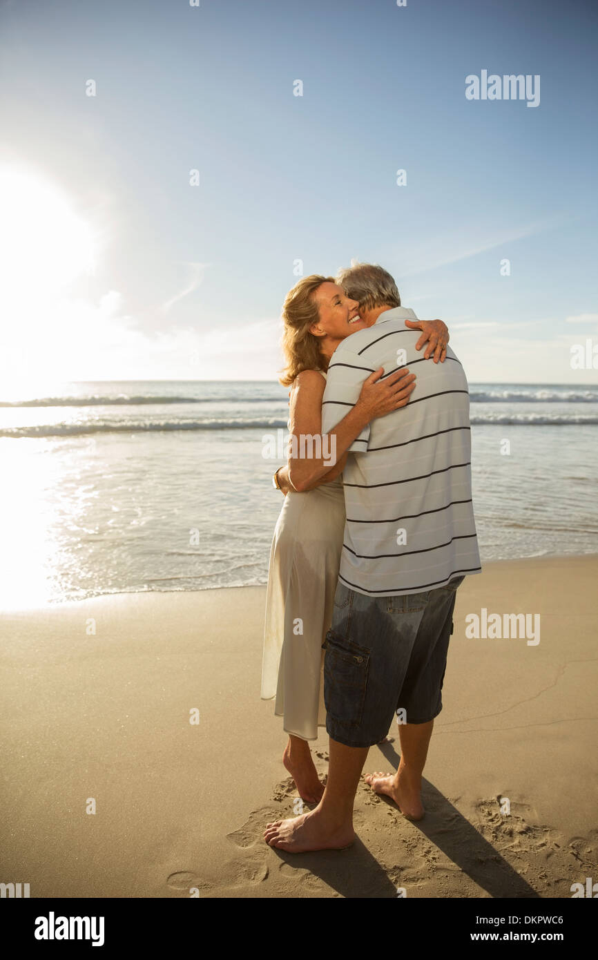 Älteres Ehepaar umarmt am Strand Stockfoto