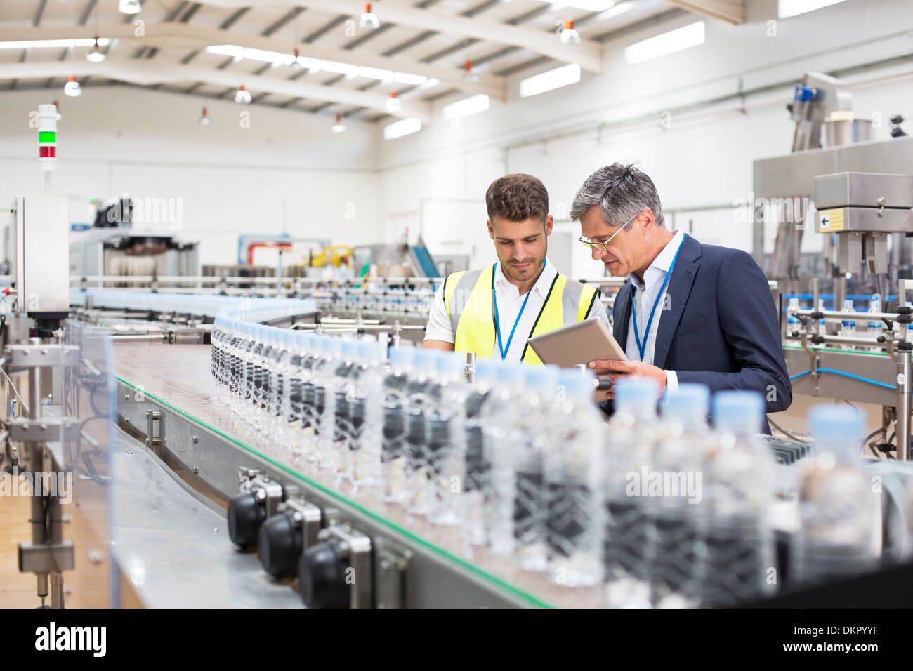 Supervisor und Manager beobachten Plastikflaschen auf Förderband Stockfoto