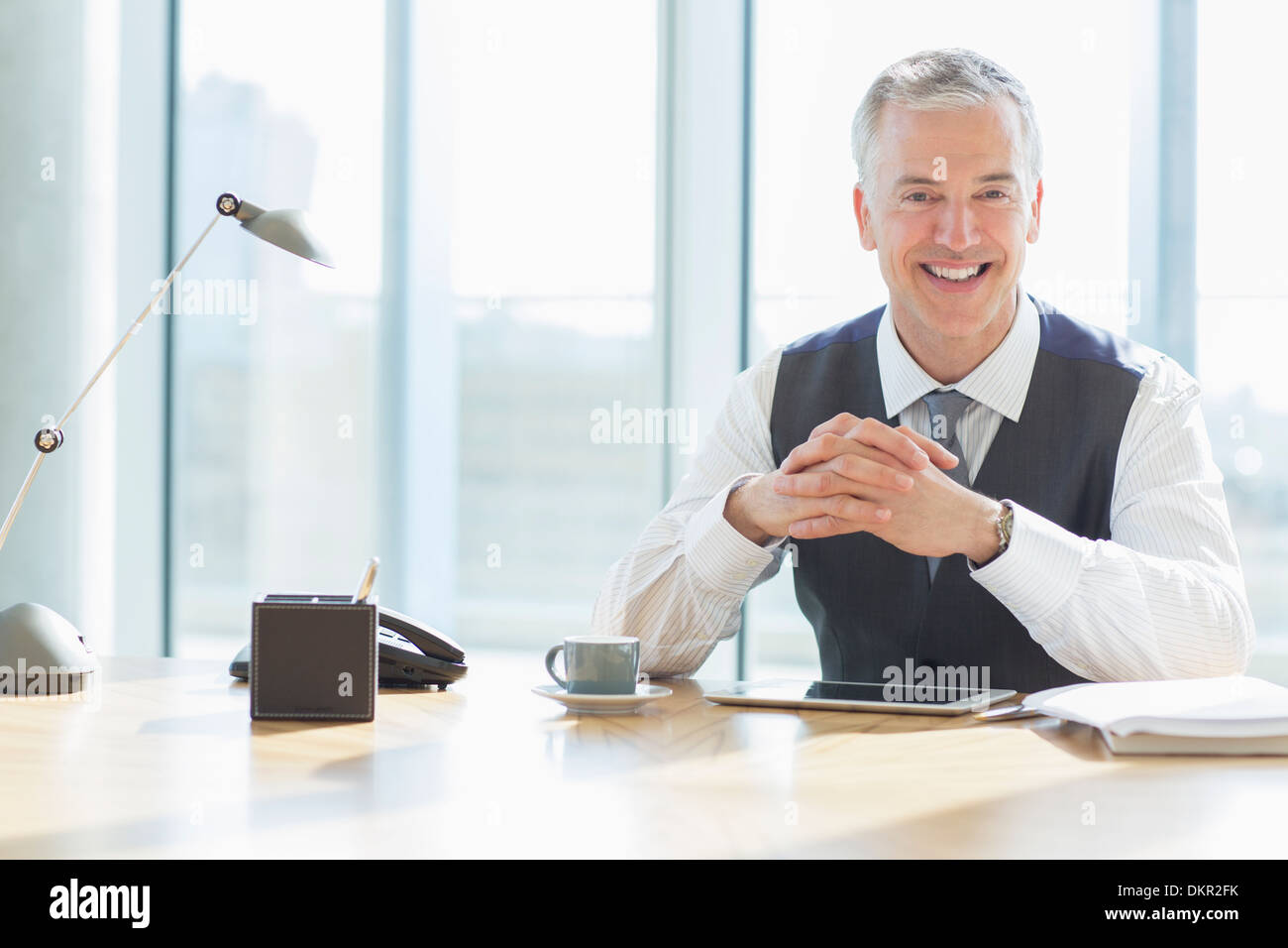 Geschäftsmann lächelnd am Schreibtisch im Büro Stockfoto
