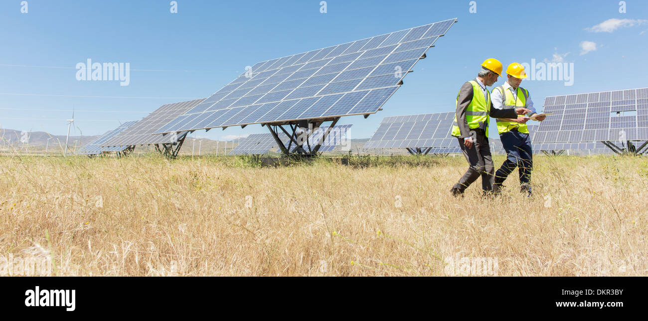 Arbeiter zu Fuß durch Sonnenkollektoren in ländlichen Landschaft Stockfoto