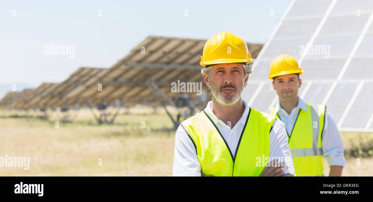 Arbeitnehmer, die durch Sonnenkollektoren in ländlichen Landschaft stehend Stockfoto