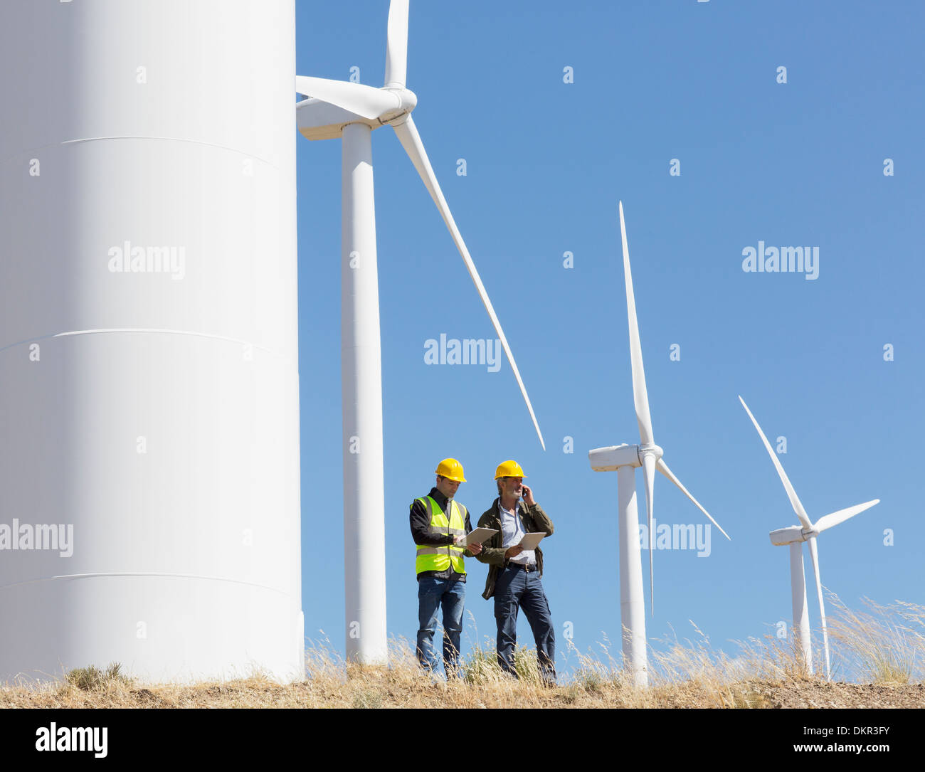 Arbeitnehmer, die durch Windkraftanlagen in ländlichen Landschaft sprechen Stockfoto